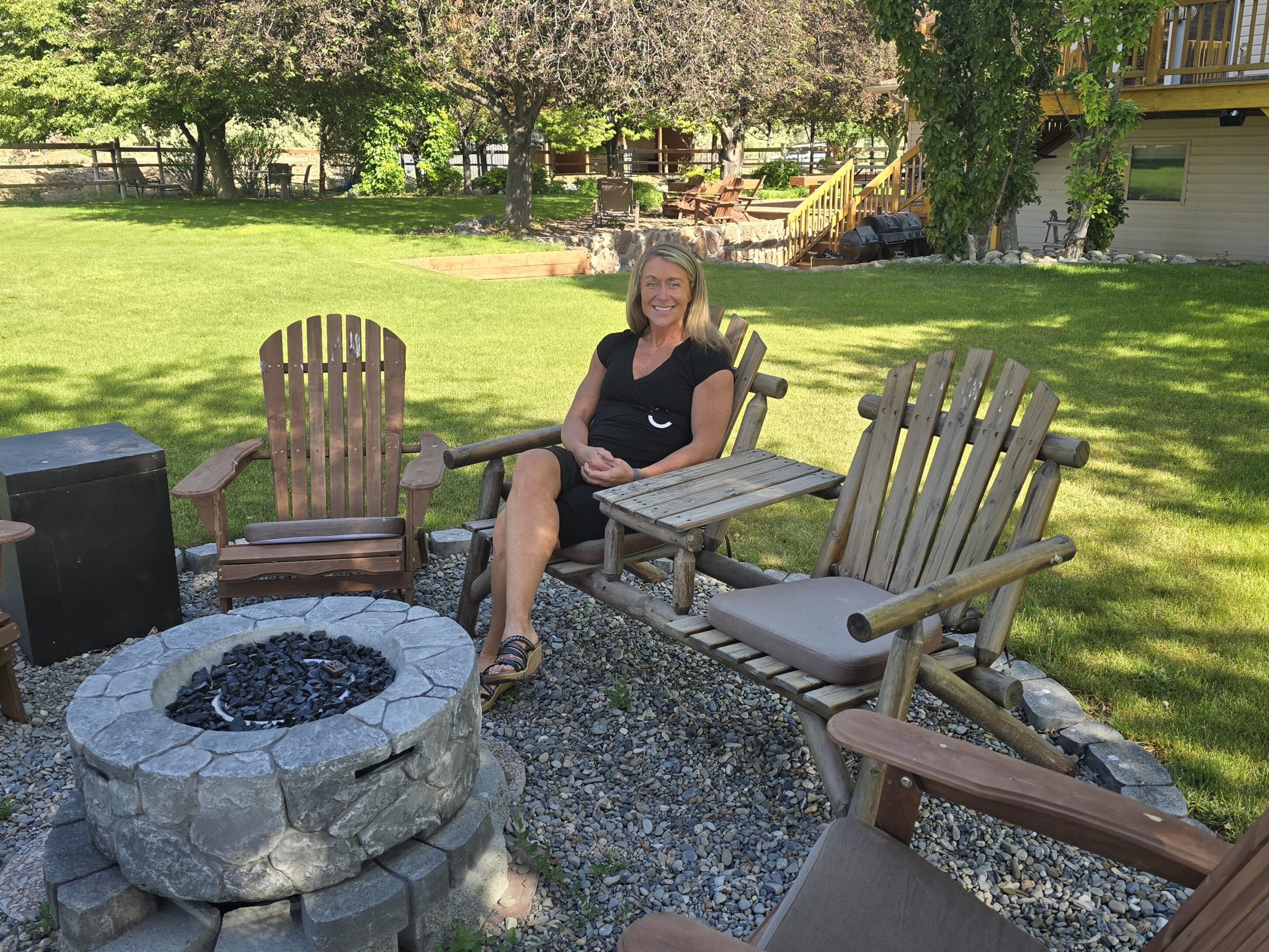 Person sitting in Adirondack chairs by fire pit