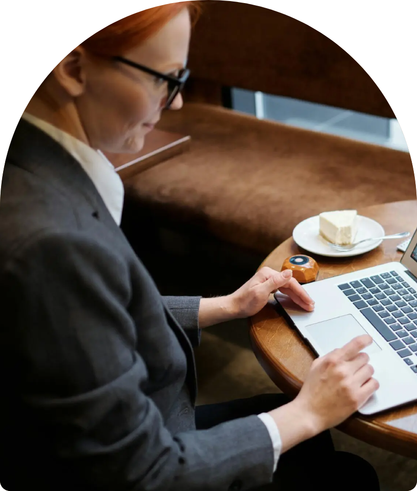 Woman using laptop at cafe table with pastry