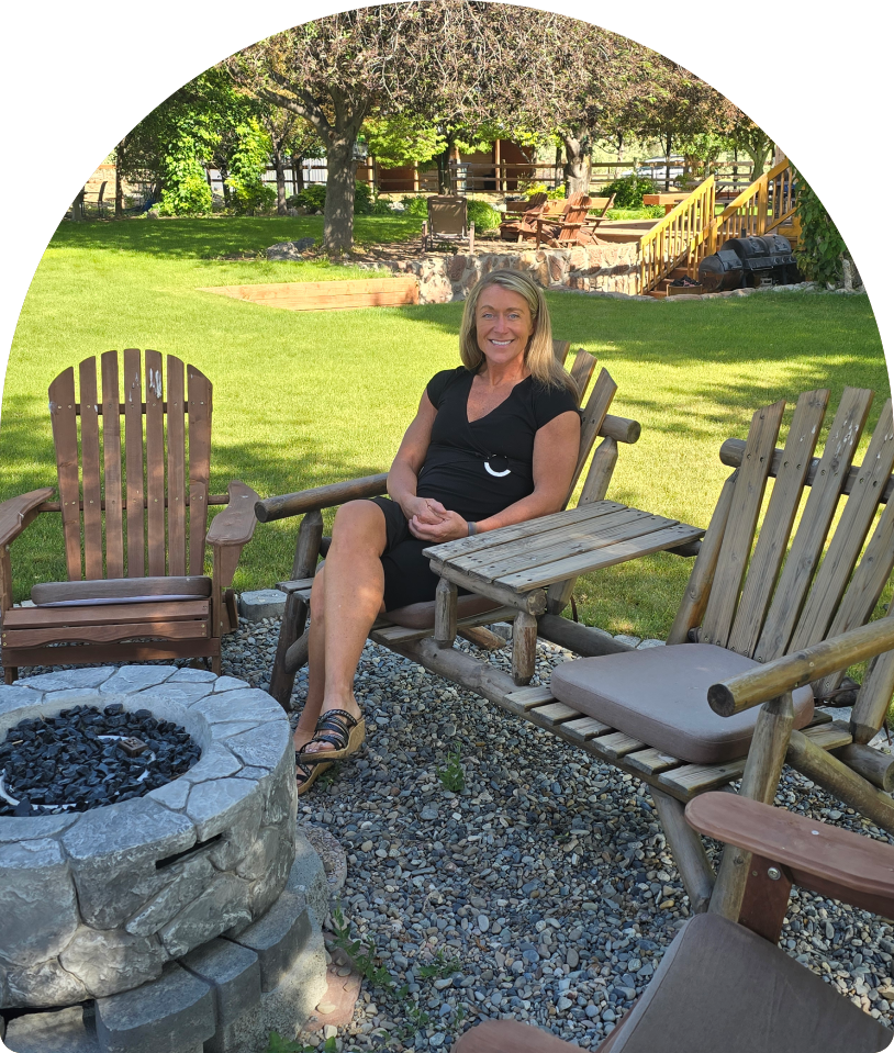 Smiling woman seated by backyard fire pit